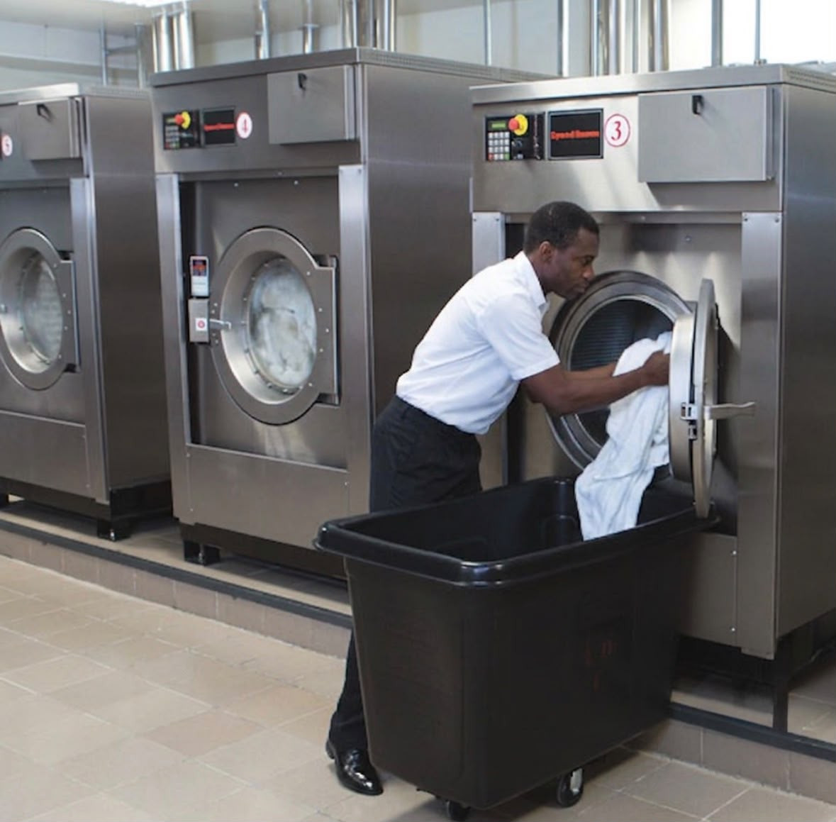 Crisp & Stitch staff member loading garments into a washer
